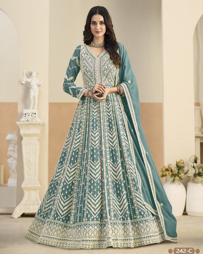 Woman wearing a traditional teal and white embroidered dress in an elegant indoor setting.