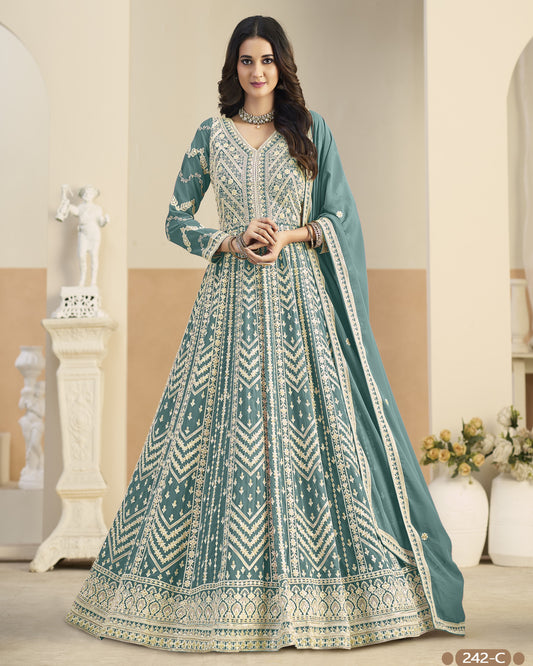 Woman wearing a traditional teal and white embroidered dress in an elegant indoor setting.