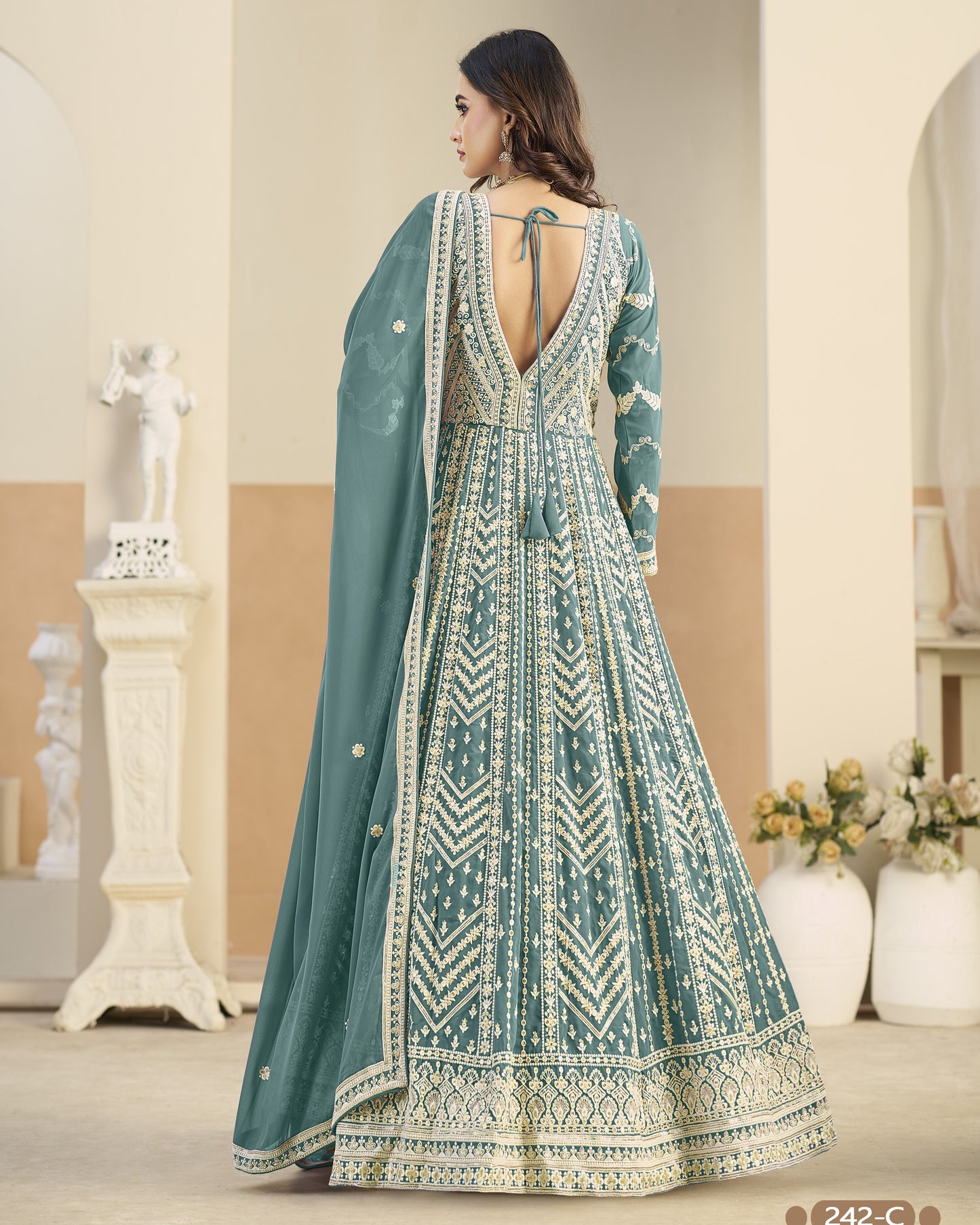 Woman wearing a teal and white patterned dress with a matching dupatta in an indoor setting.
