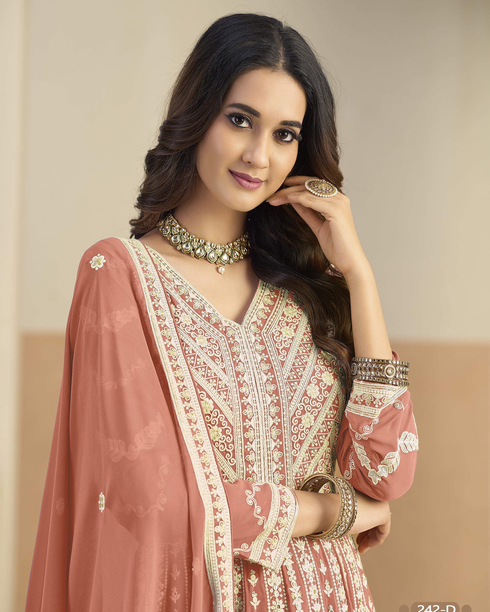 Woman wearing a traditional outfit with intricate embroidery, posing against a plain background.