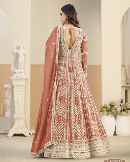 Woman wearing a traditional embroidered dress with a pink dupatta in an indoor setting.