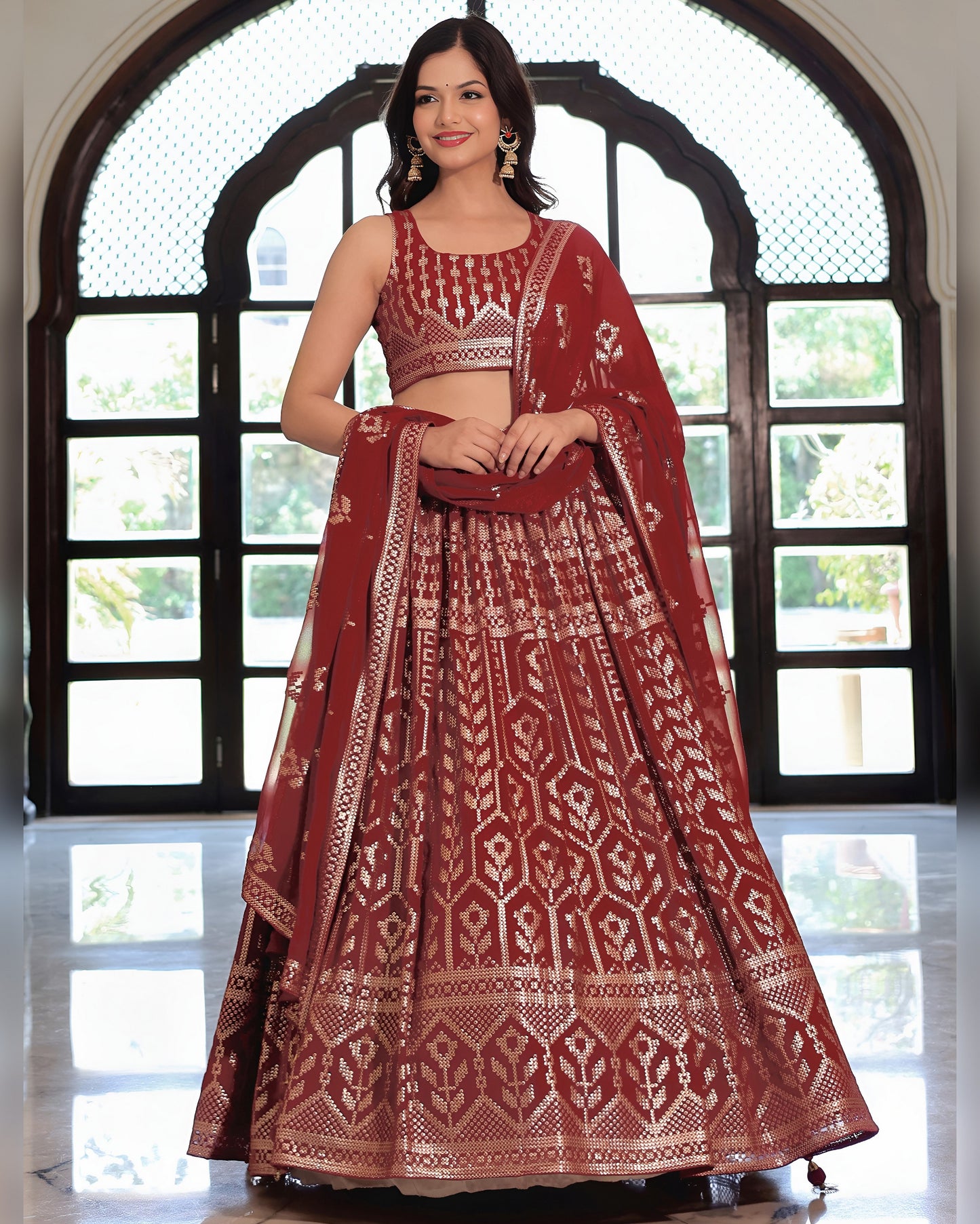 Woman wearing a traditional maroon and white embroidered lehenga in front of a large window.