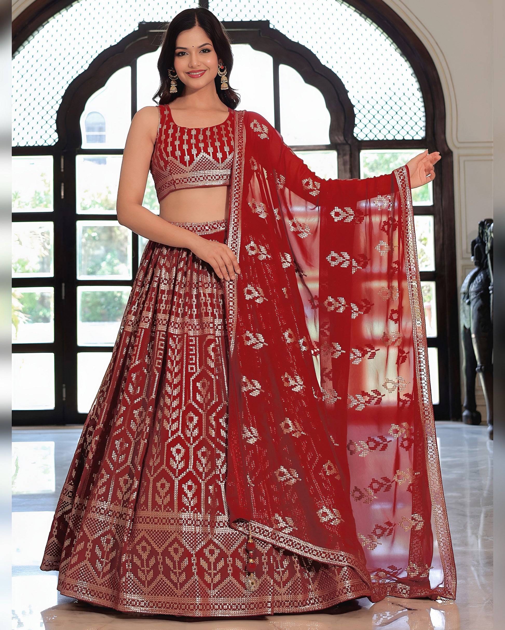 Woman in a red and white patterned traditional outfit with a matching dupatta.