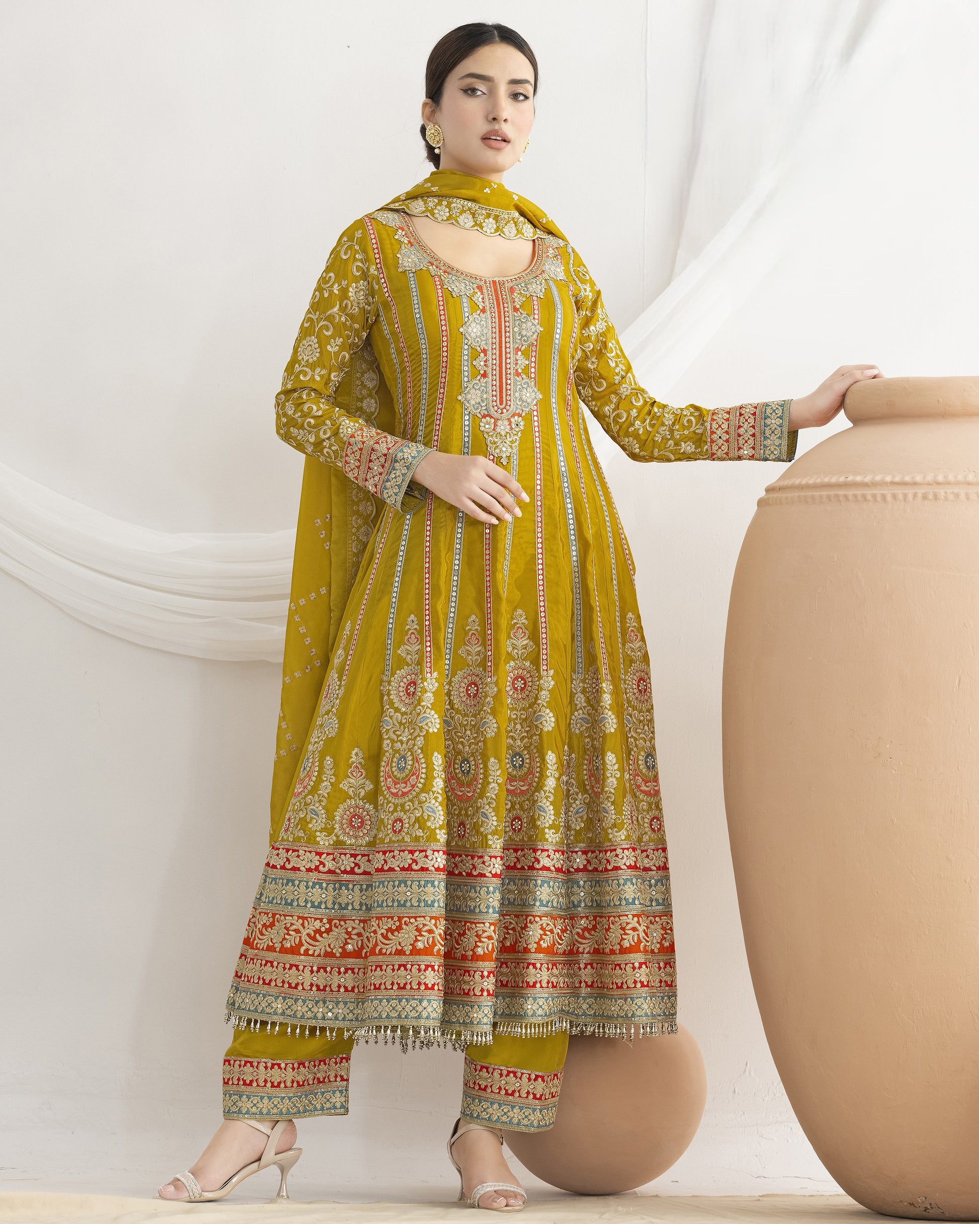 Woman wearing a yellow embroidered traditional outfit with a white background