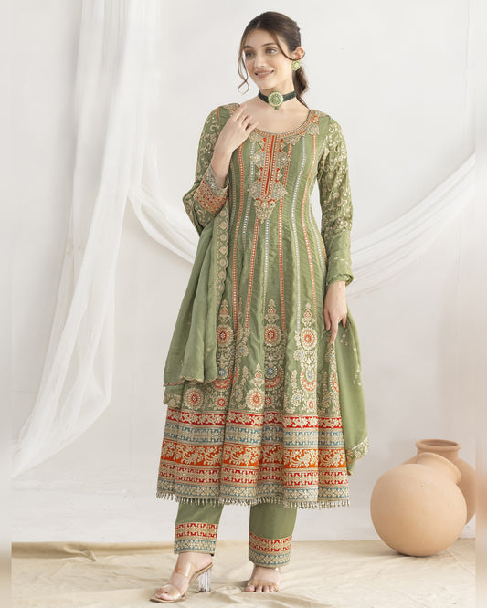 Woman wearing a green embroidered traditional outfit with a white curtain background