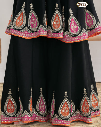 Black traditional outfit with intricate red and pink embroidery on a wooden floor.