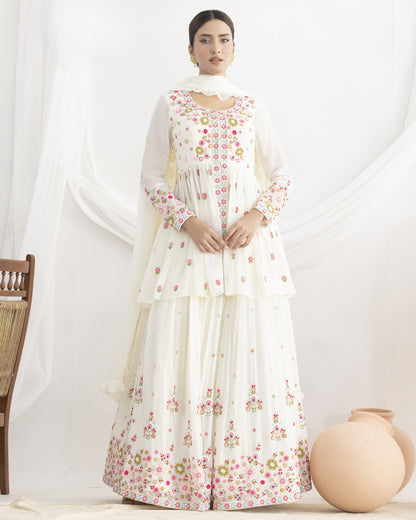 Woman wearing a white floral dress with a sheer dupatta against a white background