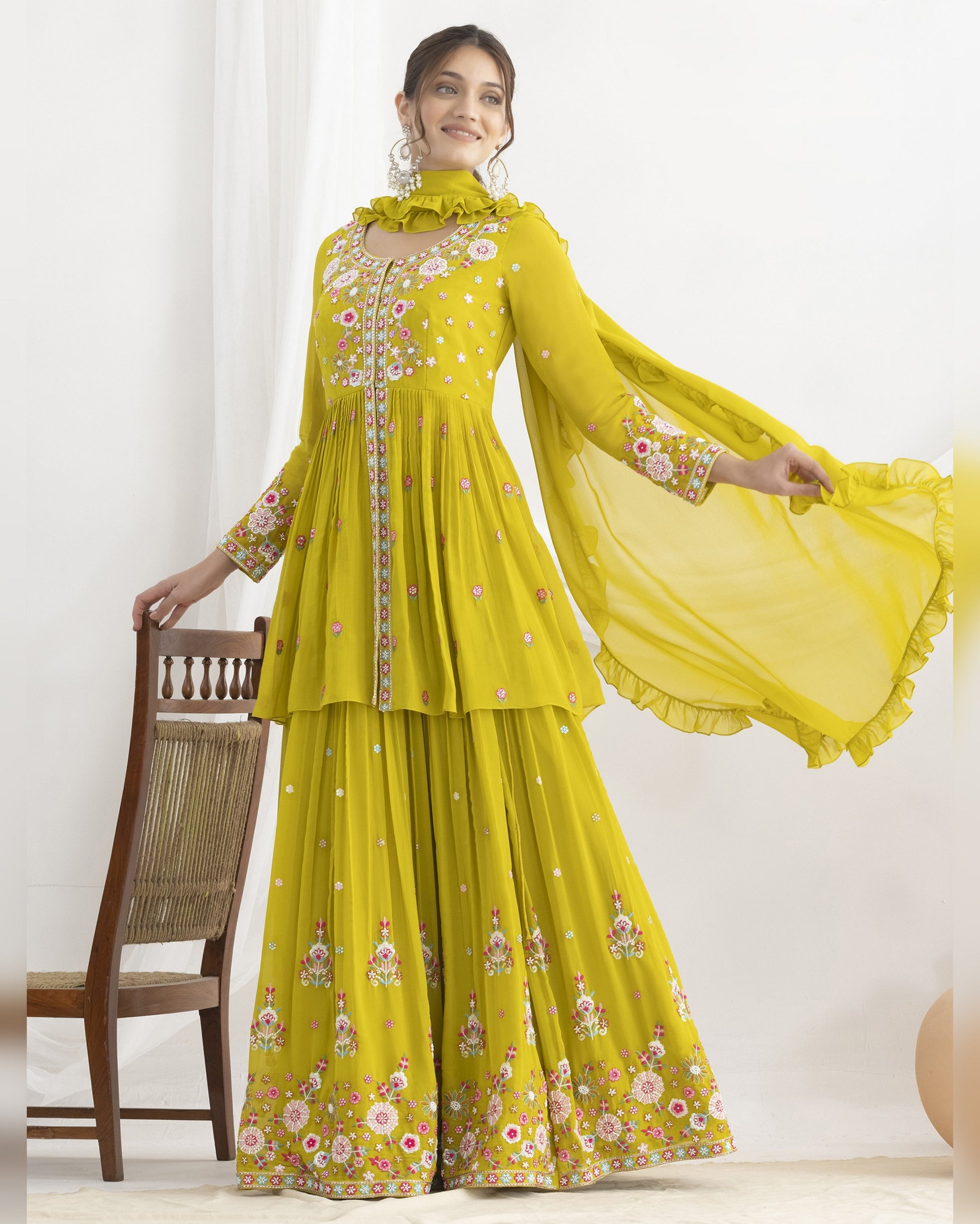 Woman wearing a yellow embroidered traditional outfit with a white background