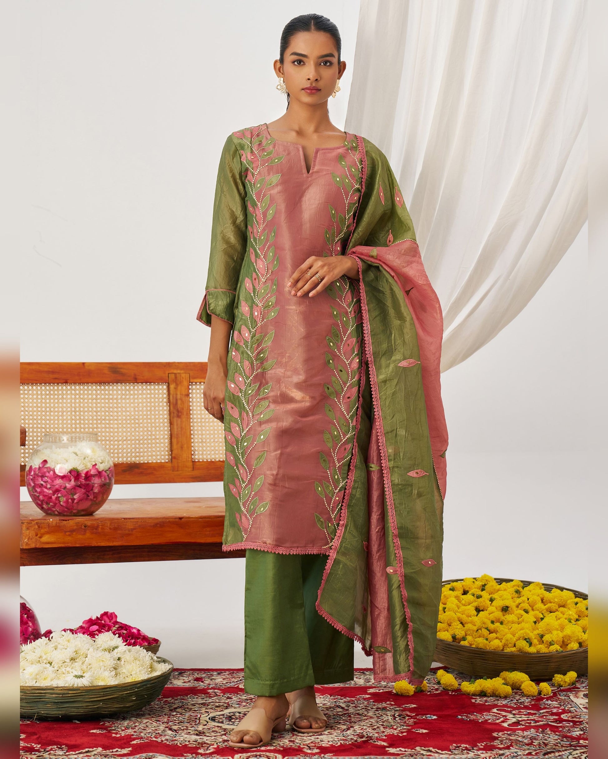 Woman wearing a traditional outfit with floral patterns in a decorated room.