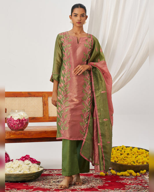 Woman wearing a traditional outfit with floral patterns in a decorated room.