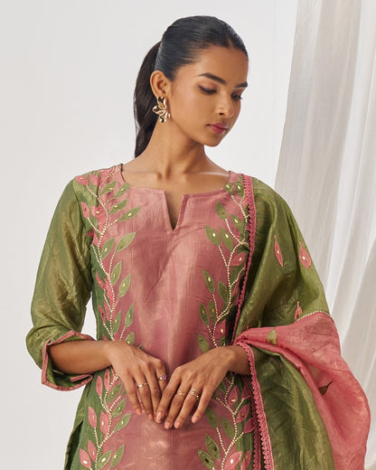 Woman wearing a traditional outfit with pink and green embroidery.