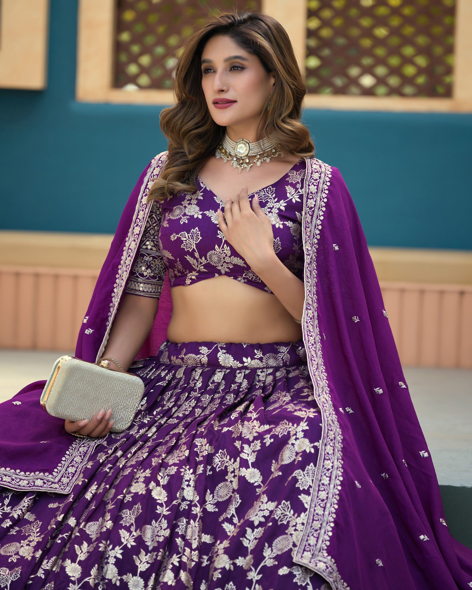 Woman in a purple traditional outfit with floral patterns indoors.