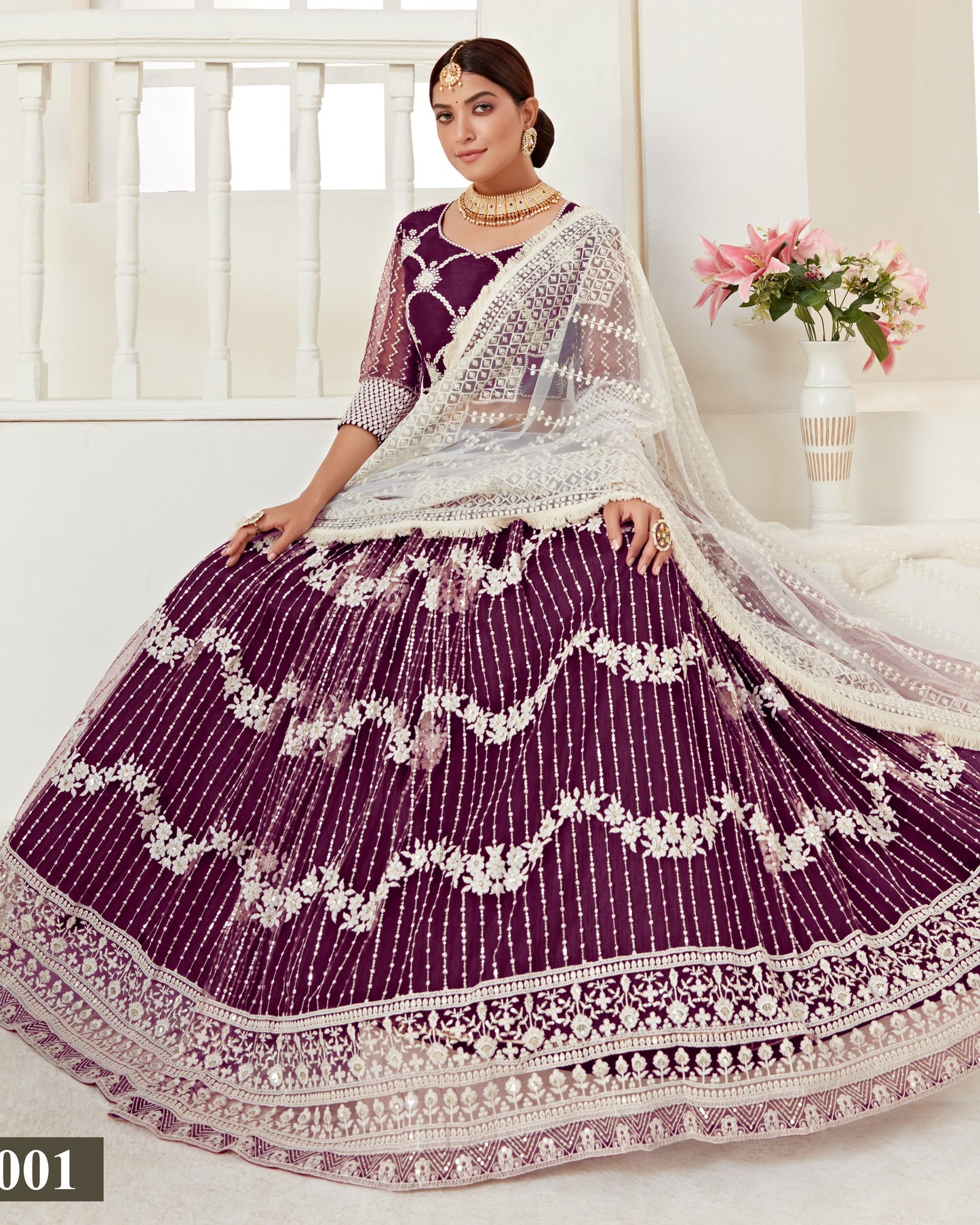 Woman wearing a traditional purple and white embroidered outfit with a white background