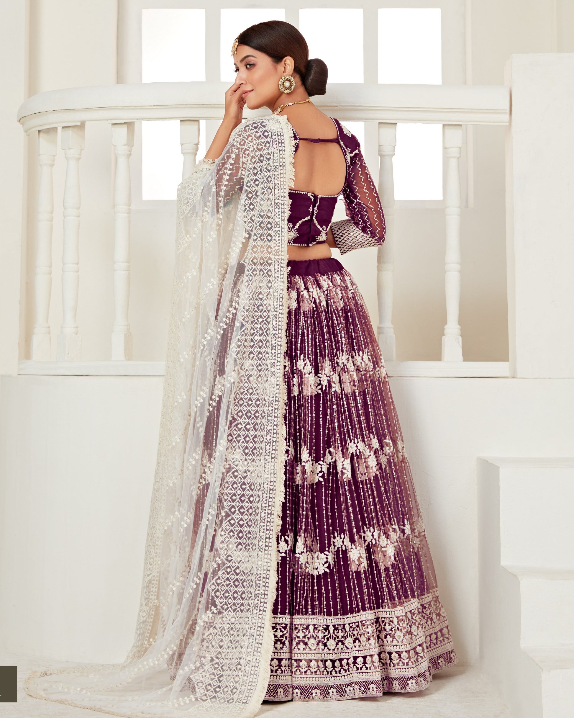 Woman in a purple and white traditional outfit standing in a bright room.