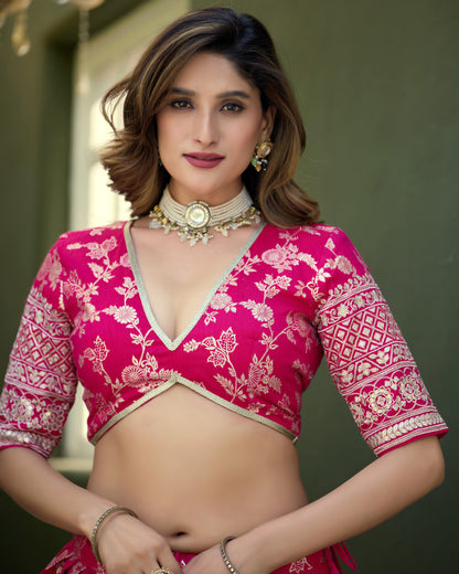 Woman wearing a pink and white traditional outfit with gold jewelry against a neutral background