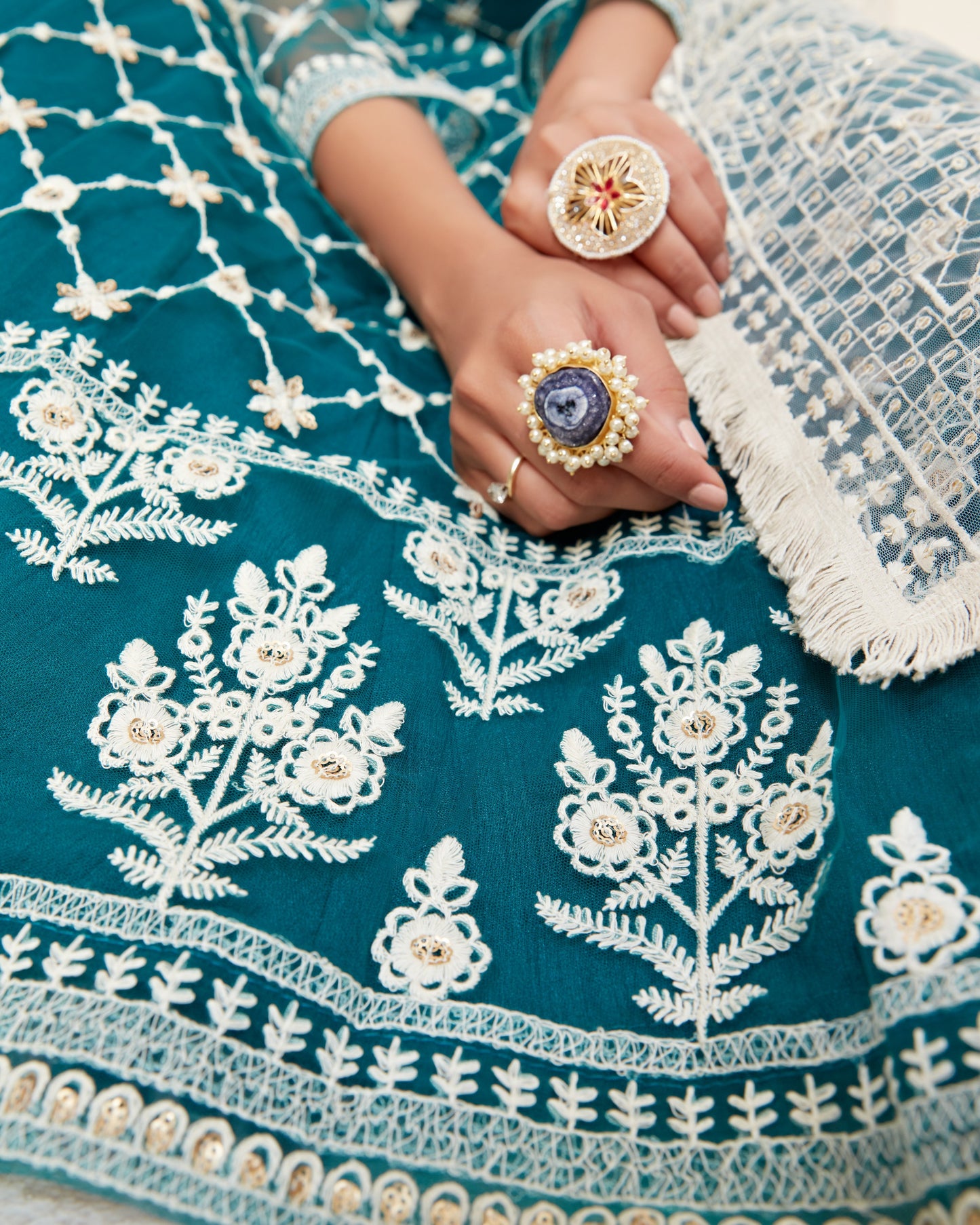 Close-up of a person wearing a blue embroidered garment with white floral patterns.