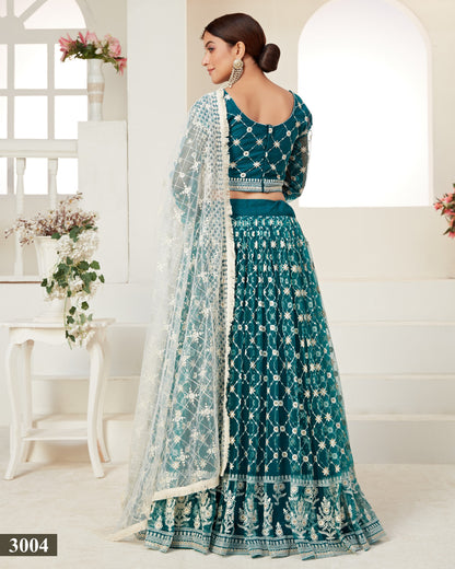 Teal embroidered lehenga with matching blouse in a bright room.