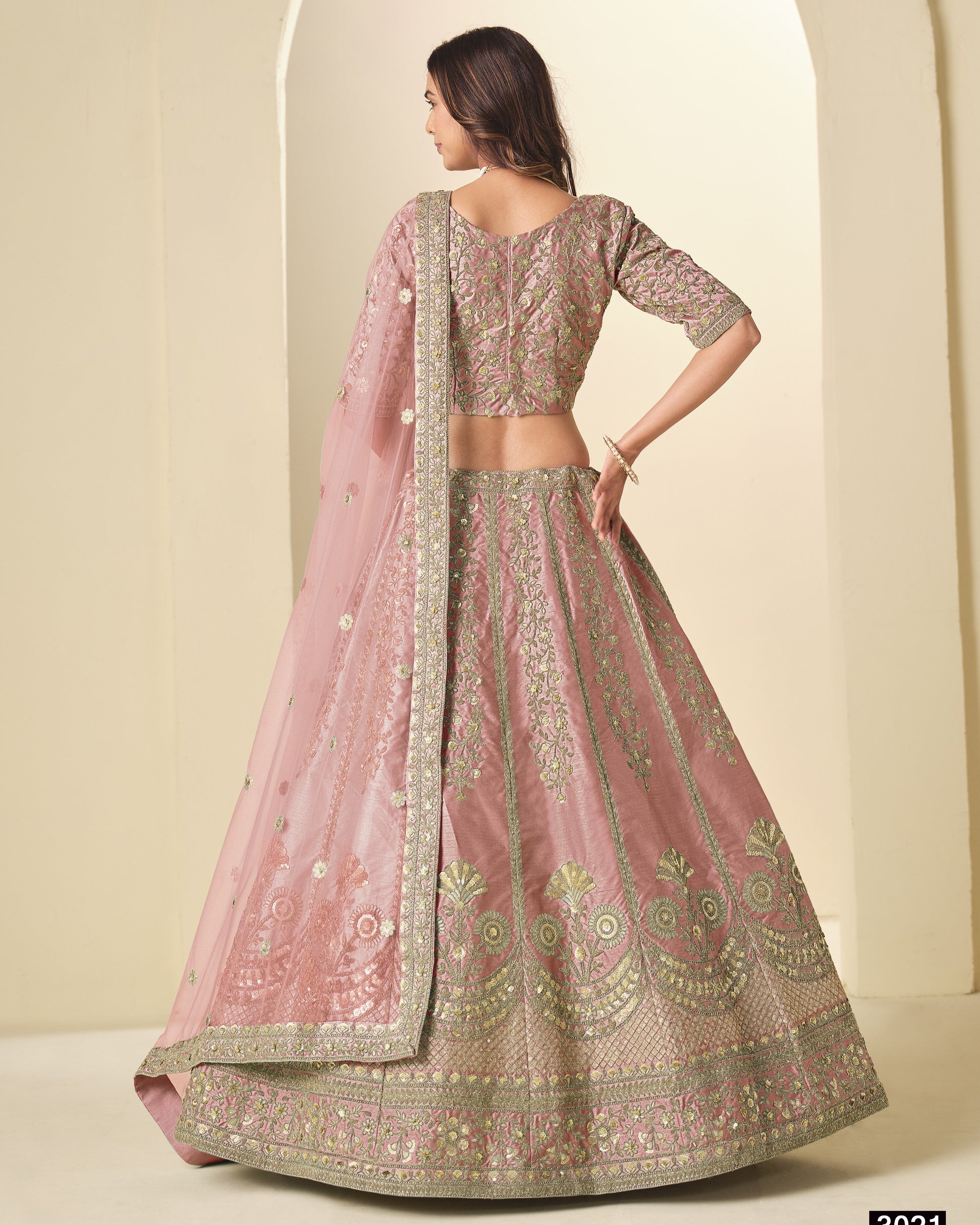 Woman wearing a traditional pink and gold embroidered lehenga with a matching dupatta.