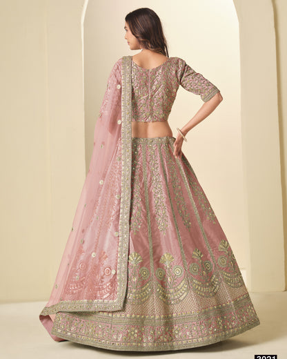 Woman wearing a traditional pink and gold embroidered lehenga with a matching dupatta.
