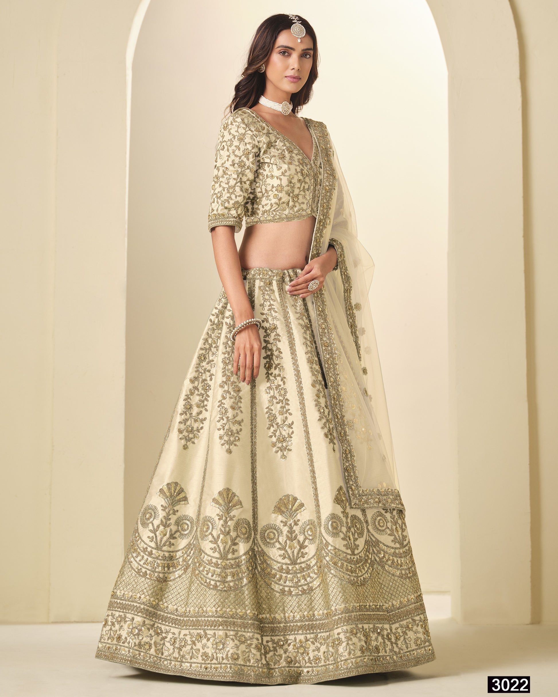 Woman wearing a traditional embroidered lehenga in a neutral setting
