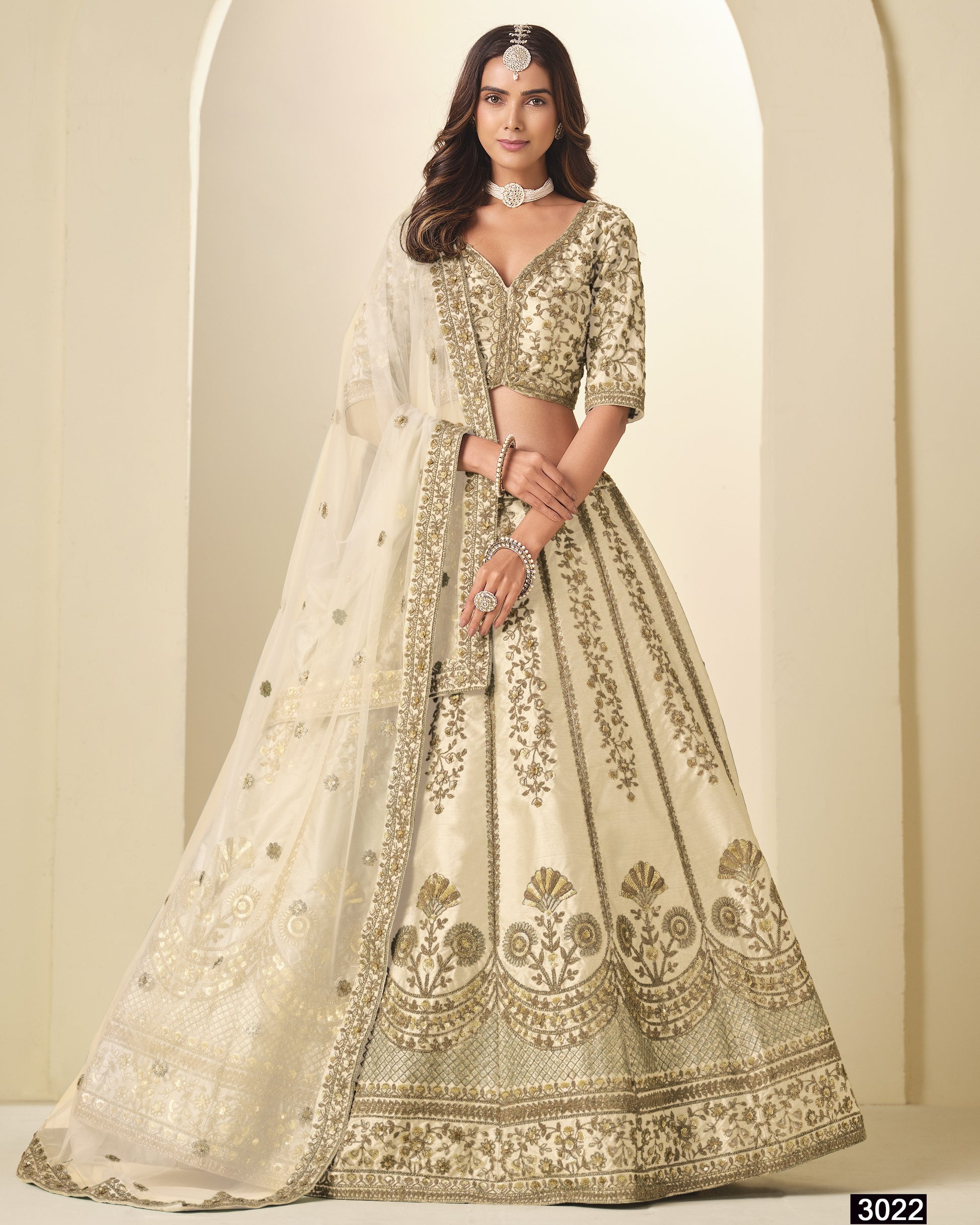 Woman wearing a traditional embroidered lehenga in a neutral setting
