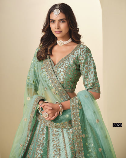 Woman wearing a light green embroidered traditional outfit with jewelry against a beige background