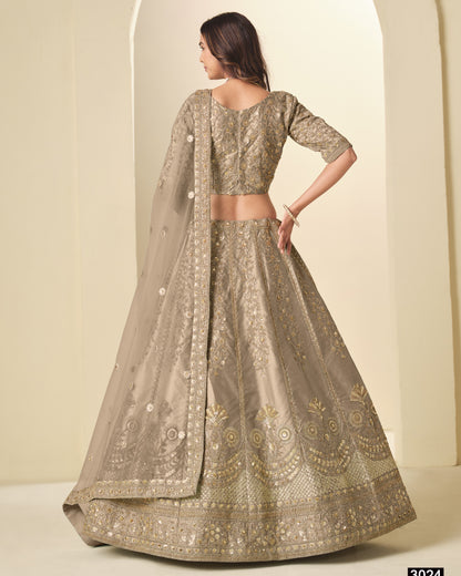 Woman wearing a traditional embroidered outfit with a sheer dupatta against a plain background