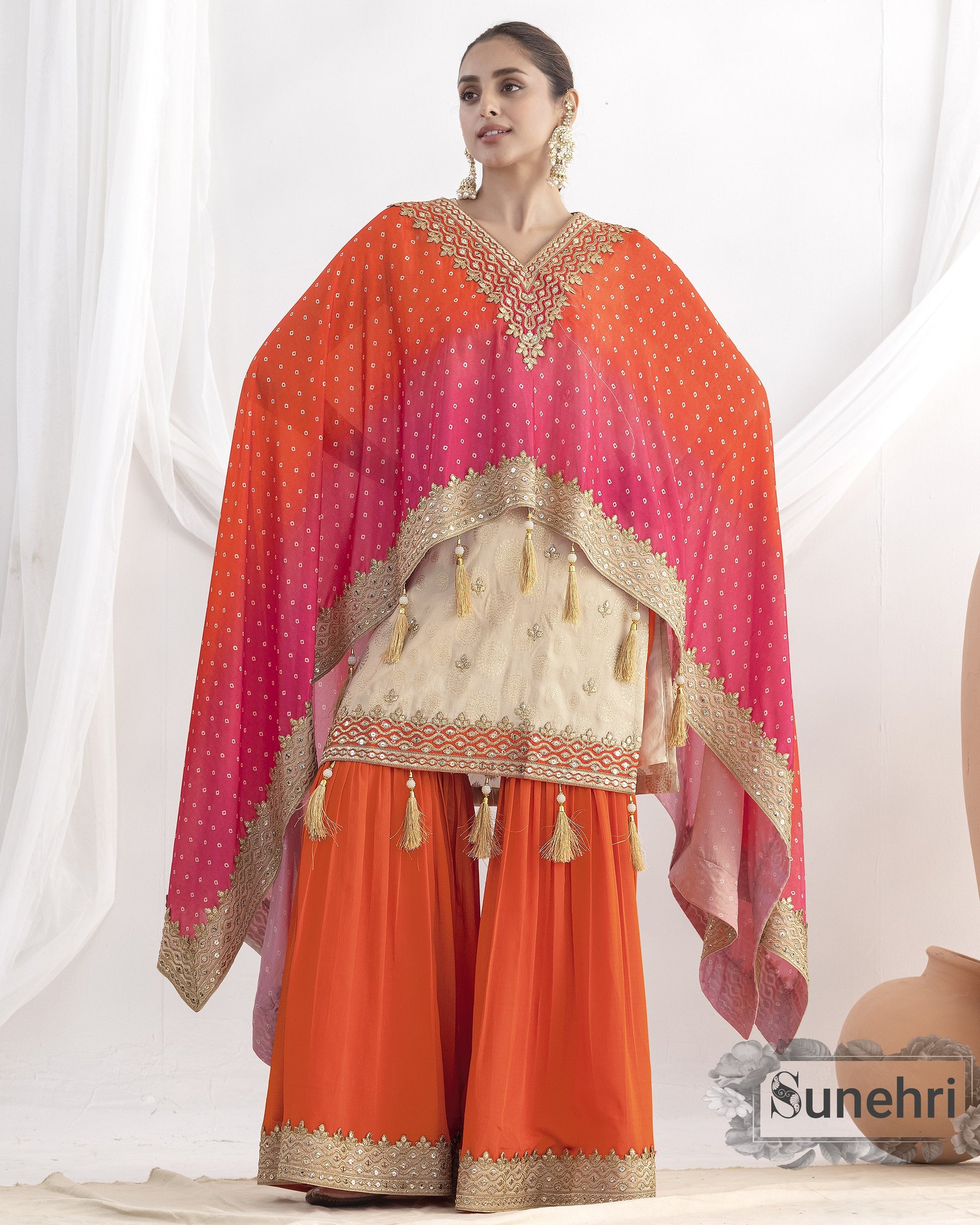 Woman wearing an orange and pink traditional outfit with a matching dupatta on a white background