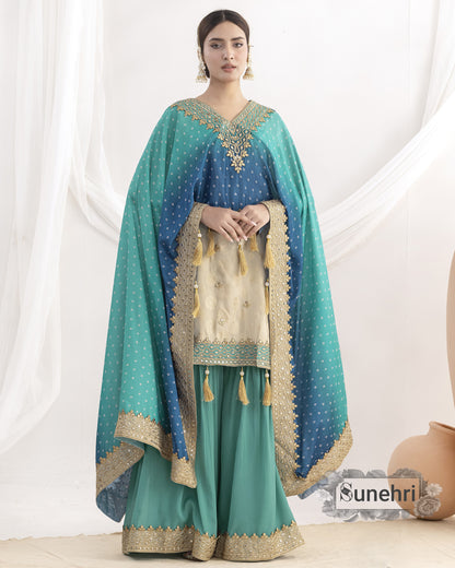 Woman wearing a teal and blue traditional outfit with gold embroidery against a white background