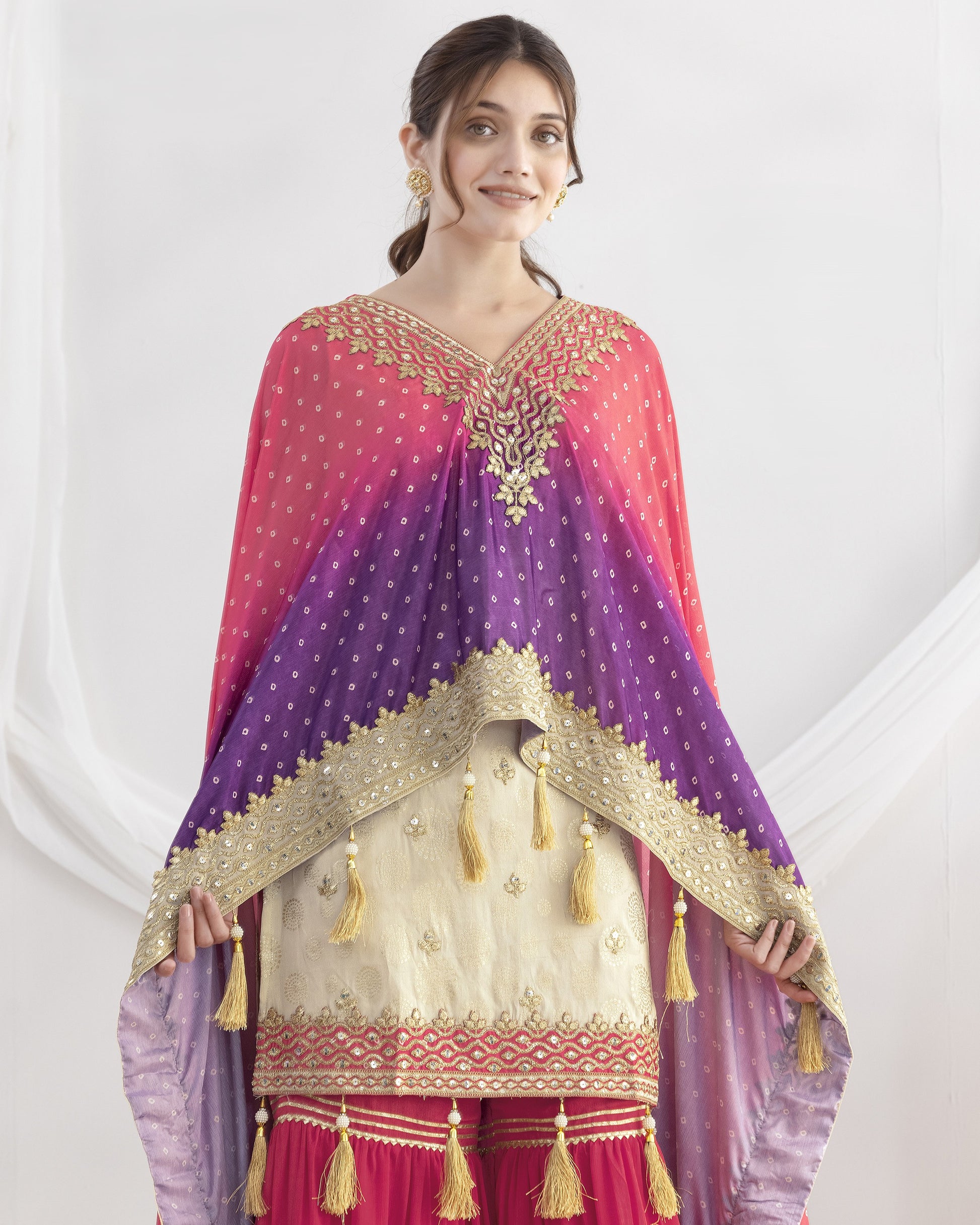 Woman wearing a traditional outfit with a pink and purple dupatta on a white background