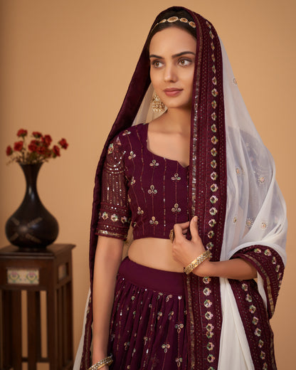 Woman wearing a traditional maroon and white outfit with a matching dupatta against a beige background.