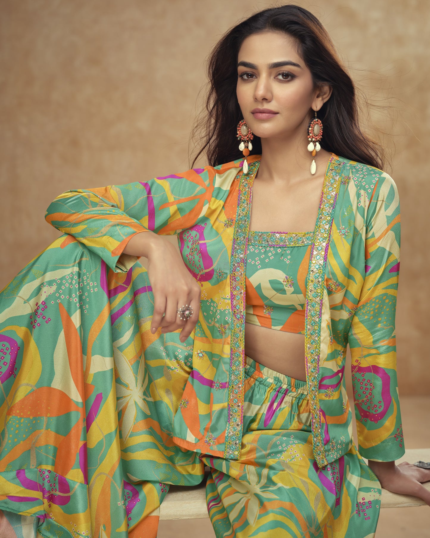 Woman wearing a colorful traditional outfit with a patterned jacket and pants against a beige background