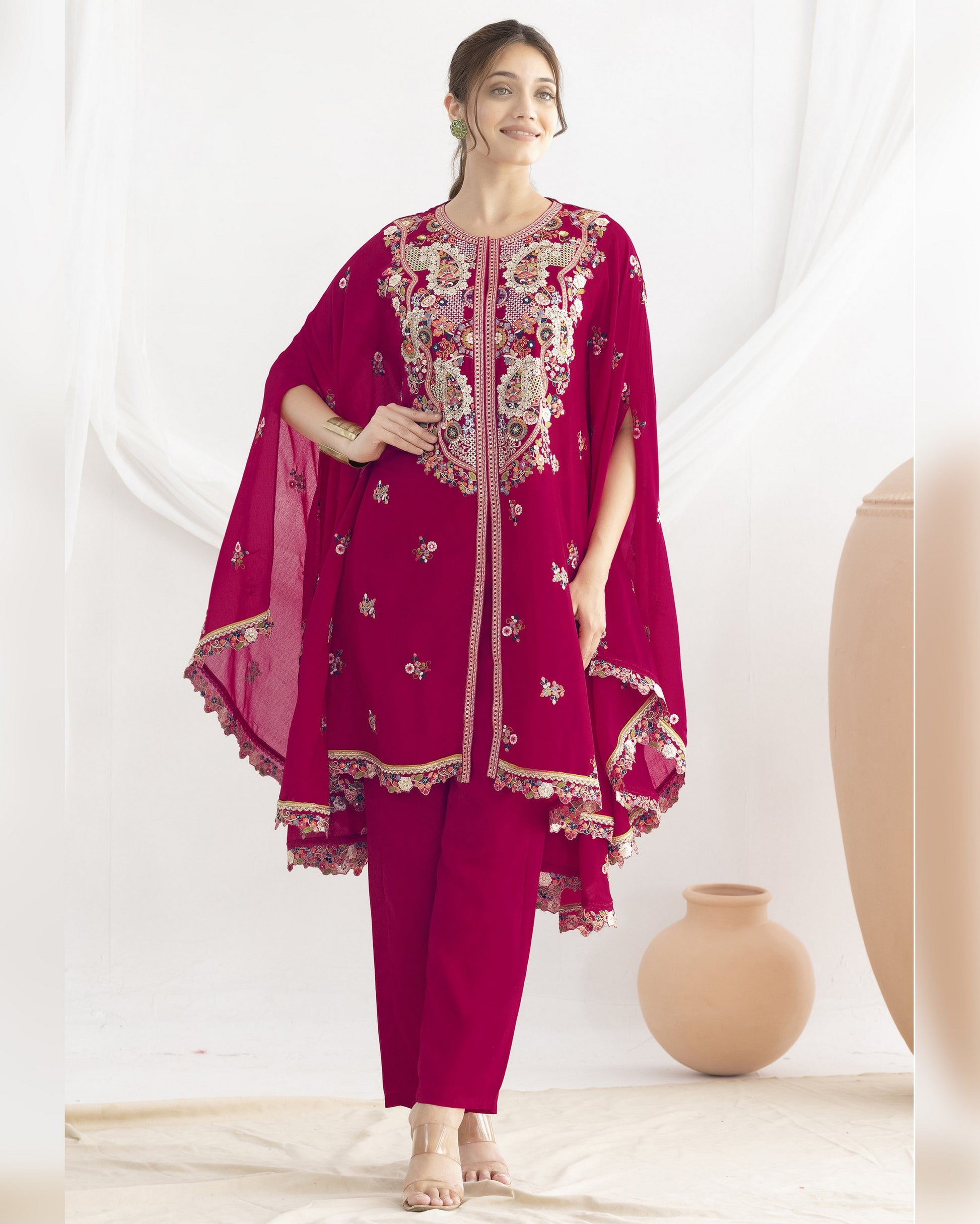 Woman wearing a magenta embroidered traditional outfit with a white background