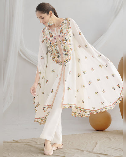 Woman wearing a white embroidered outfit with a sheer dupatta against a neutral background