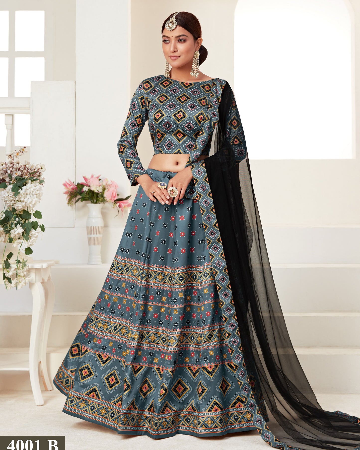 Woman wearing a traditional patterned outfit with a black dupatta in a bright room.