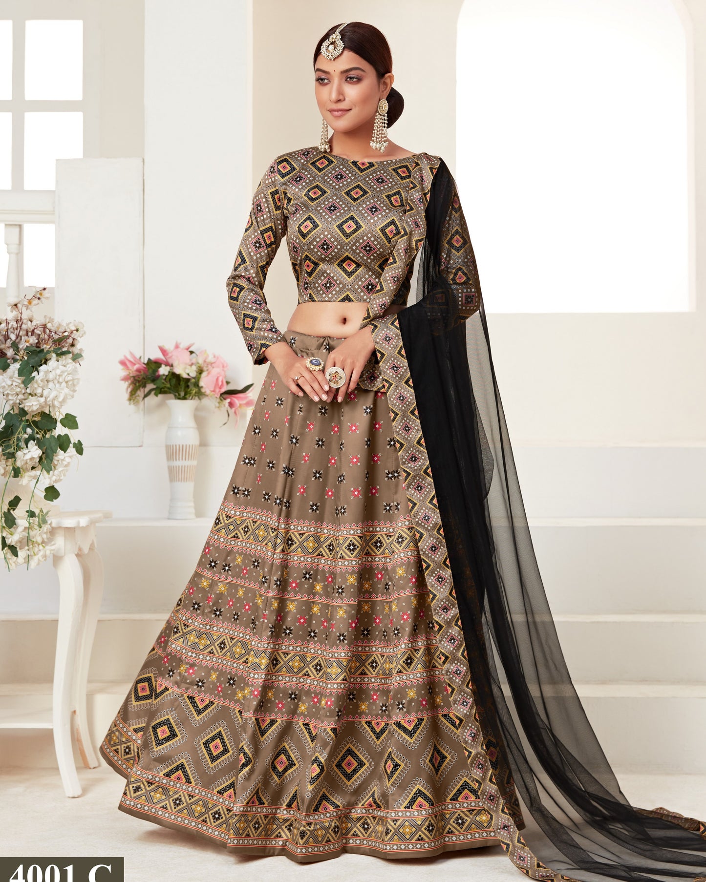 Woman wearing a patterned traditional outfit with a black dupatta in a bright room.