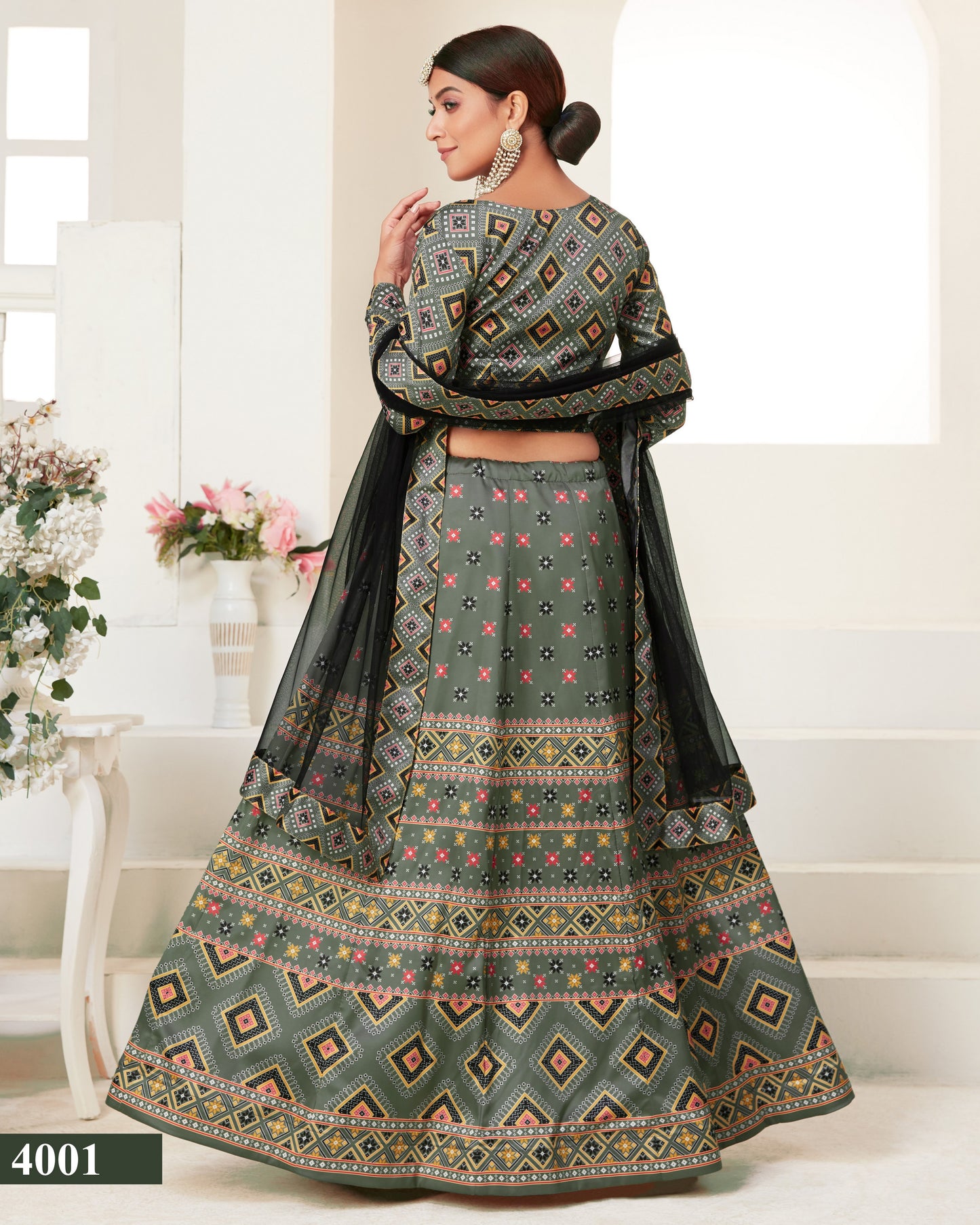 Woman wearing a traditional patterned outfit with a black dupatta in a minimalistic setting.
