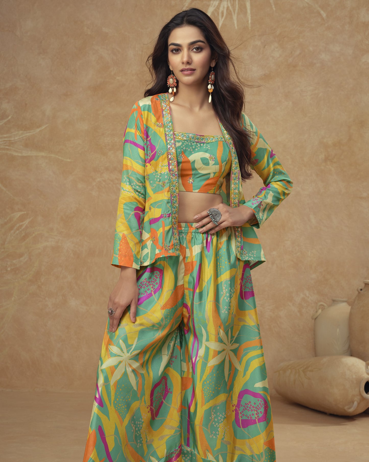 Woman wearing a colorful traditional outfit with a patterned jacket and pants against a beige background.