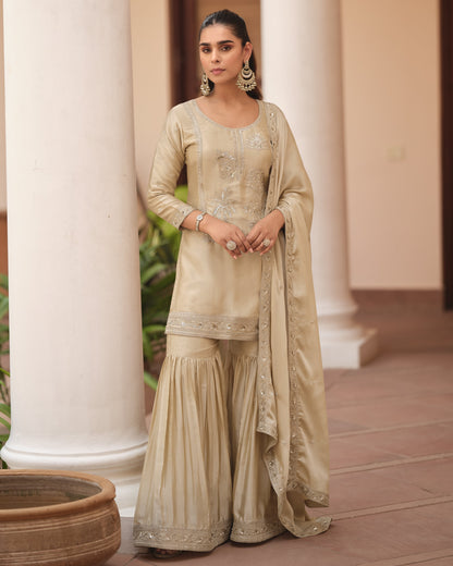 Woman in a traditional beige outfit standing in front of white columns.