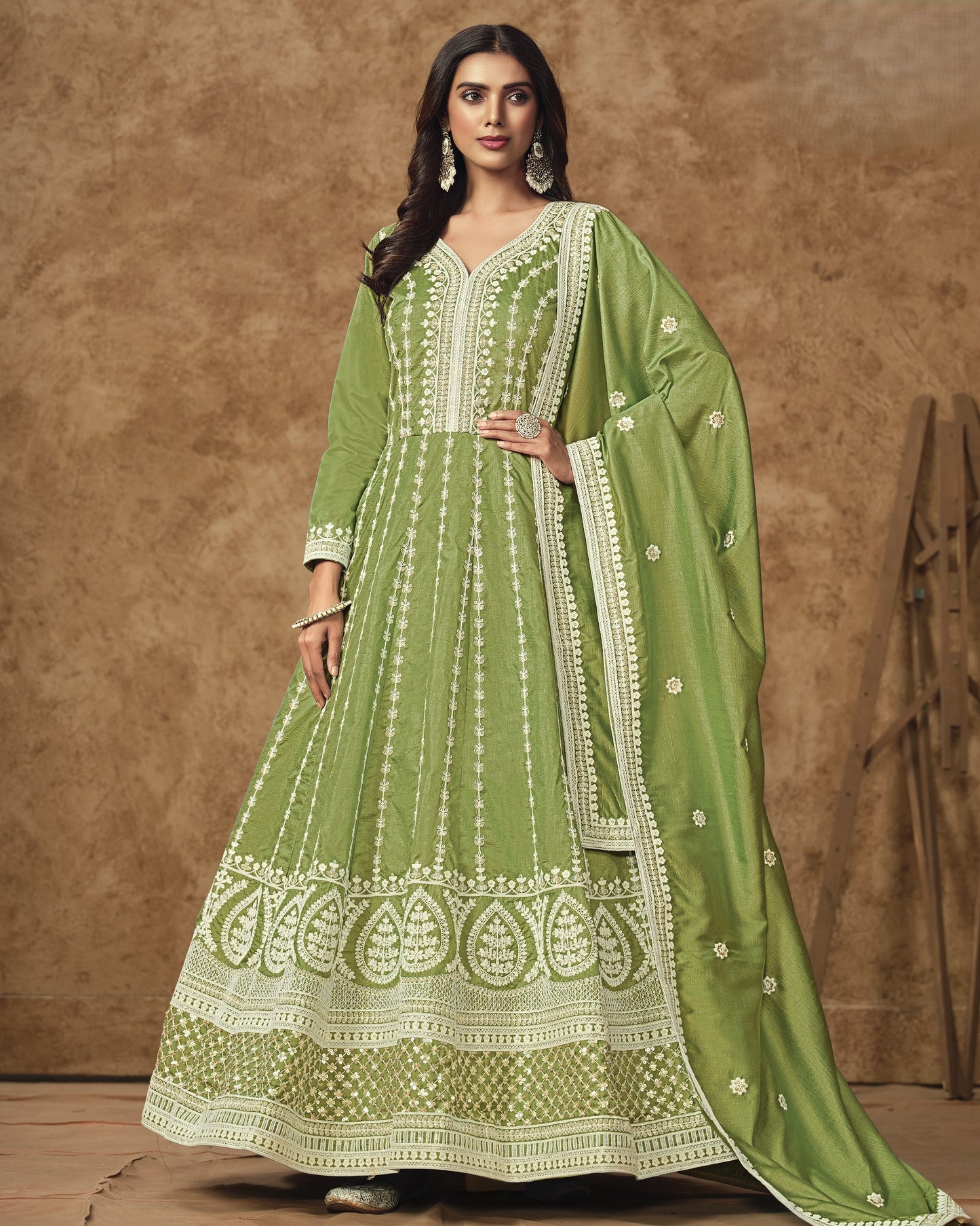 Woman wearing a green embroidered traditional outfit against a brown background