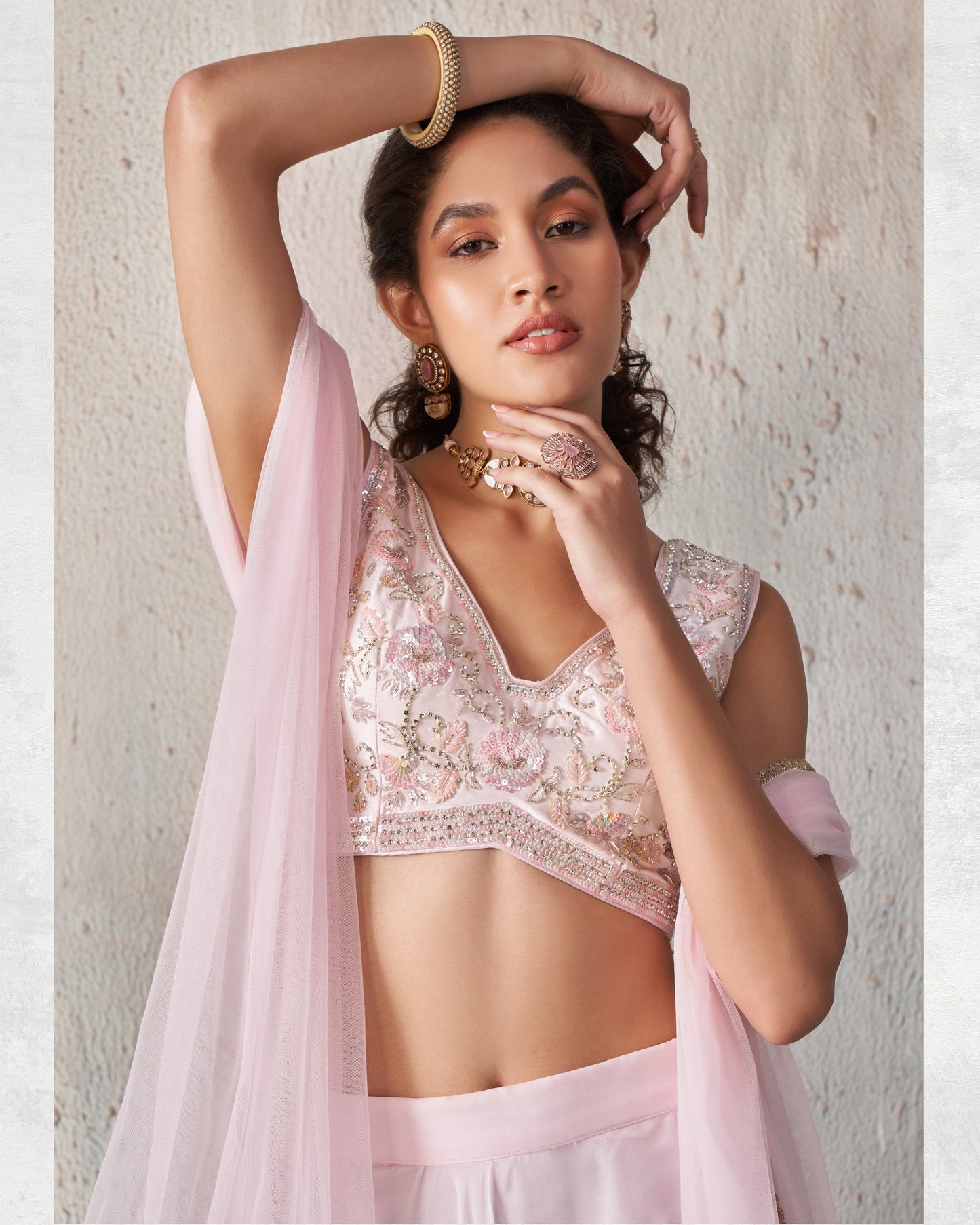 Woman wearing a light pink traditional outfit with floral patterns against a neutral background