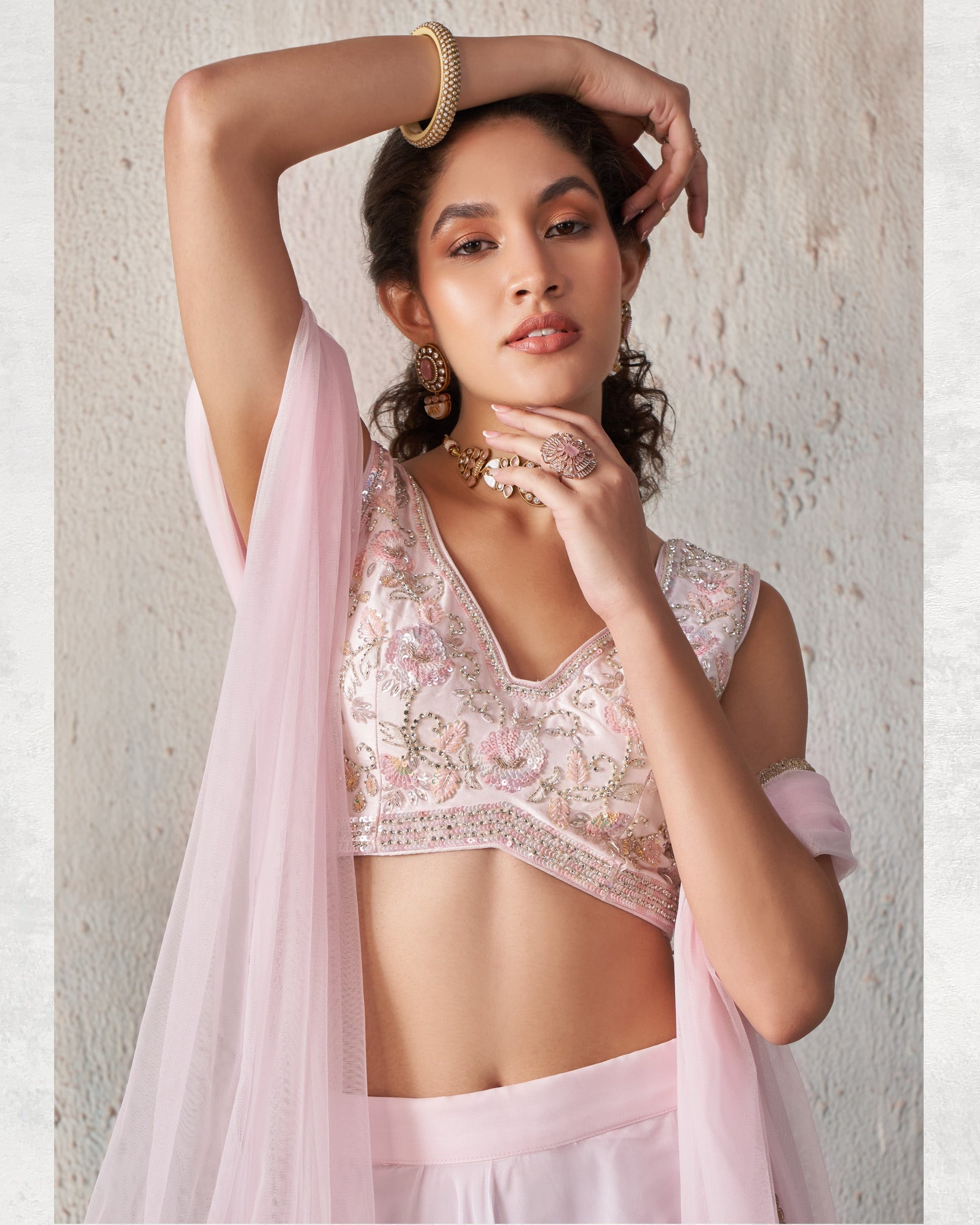 Woman wearing a light pink traditional outfit with floral patterns against a neutral background