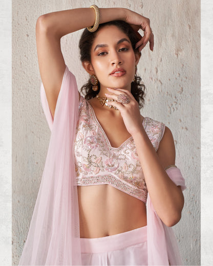 Woman wearing a light pink traditional outfit with floral patterns against a neutral background