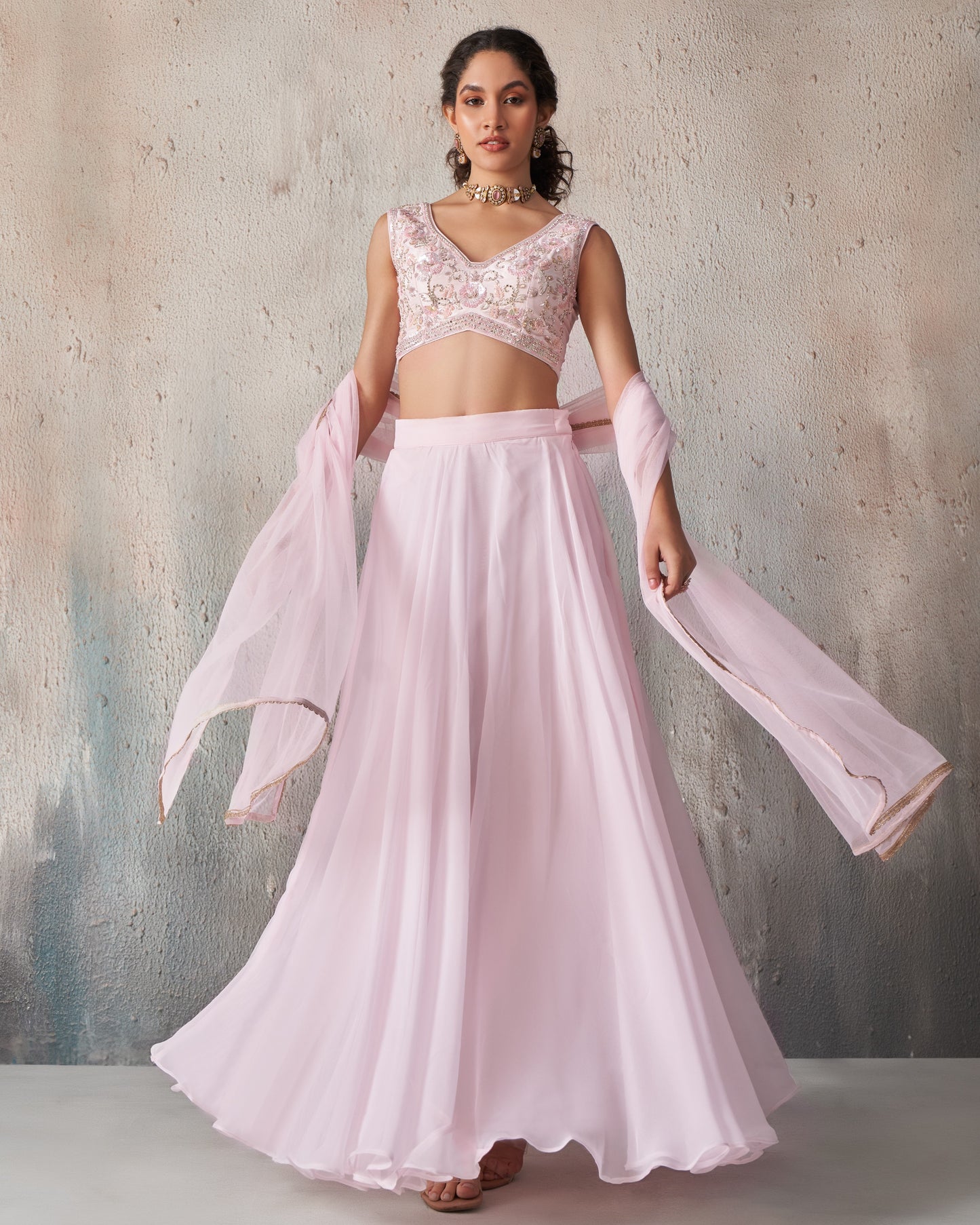 Woman wearing a pink traditional outfit with a textured gray background