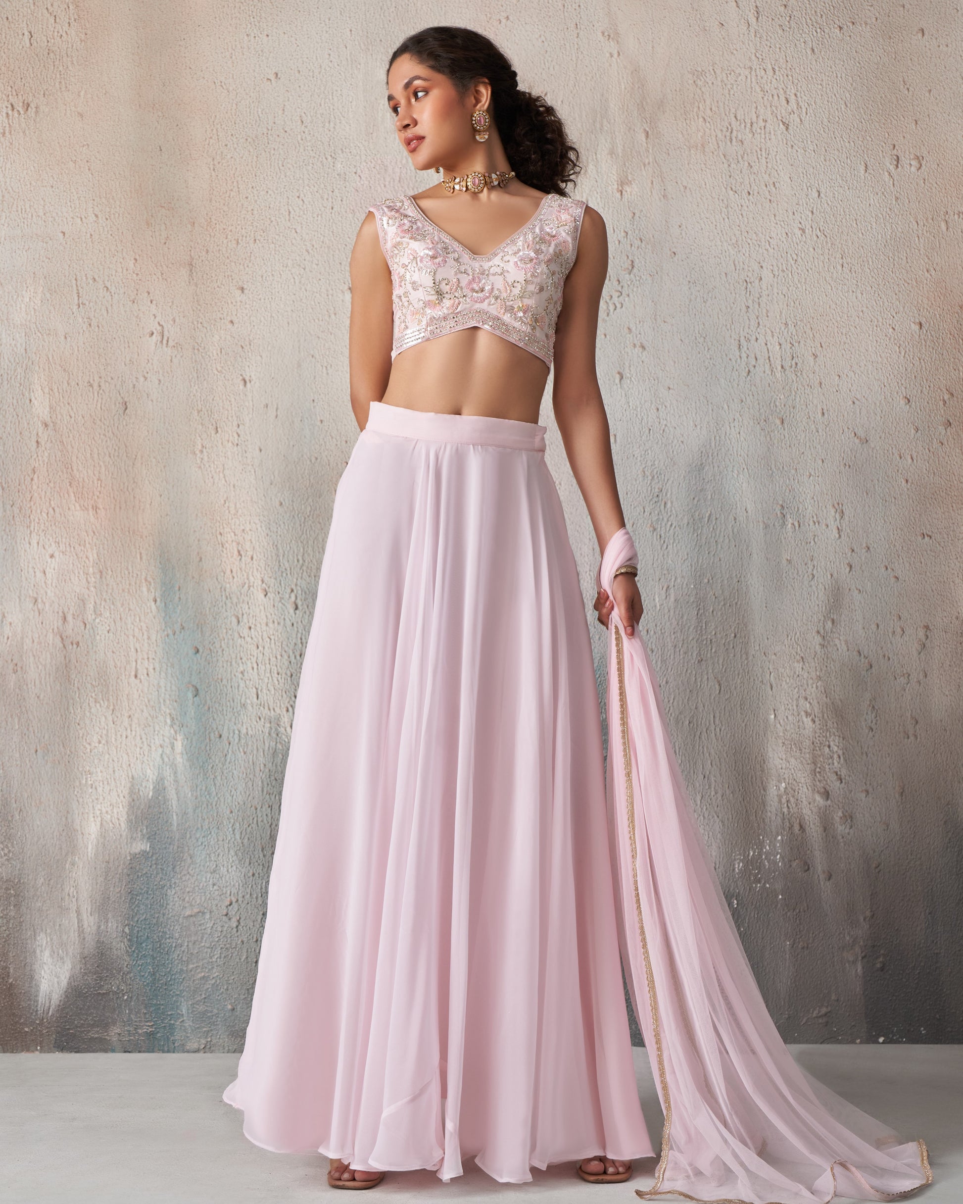 Woman wearing a pink saree with a textured wall background