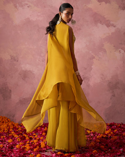 Woman in a yellow outfit standing on flower petals with a pink background