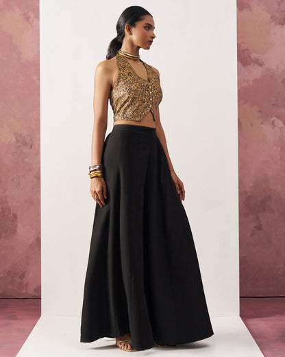 Woman wearing a gold sequin top and black skirt against a pink and white background