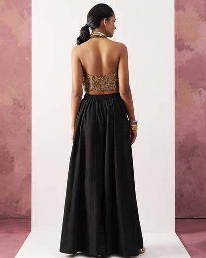 Woman wearing a black and gold evening gown with a white background