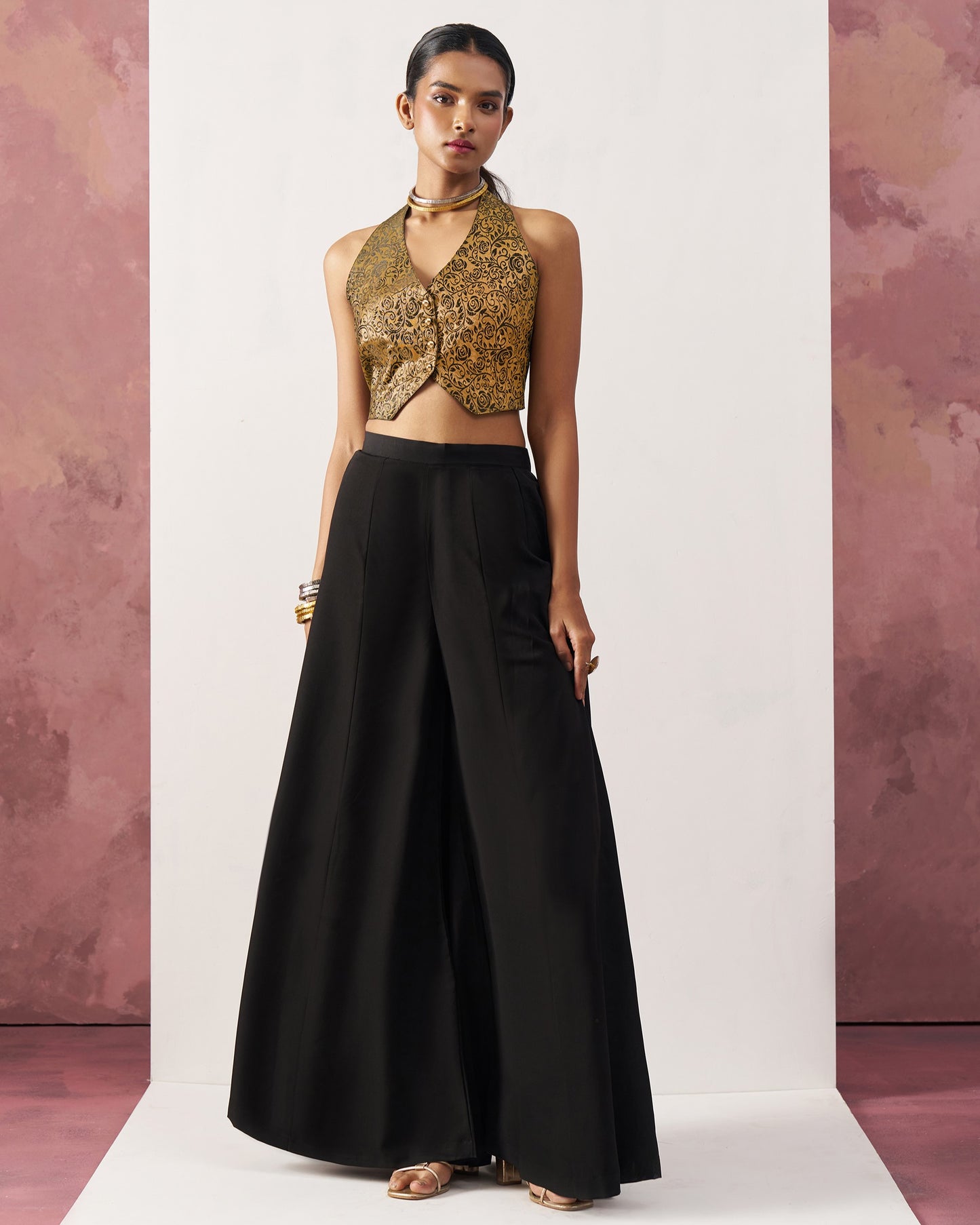 Woman wearing a gold sequin top and black skirt against a white background