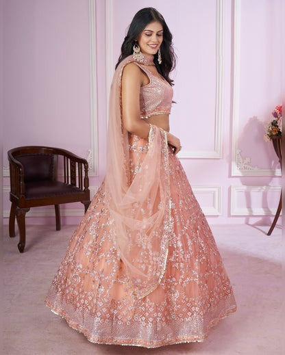 Woman in a peach embroidered lehenga in a decorated room
